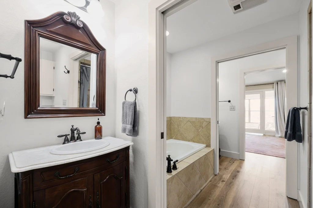 Barn House Jack-and-Jill bathroom — central soaking tub connecting two bedrooms with two toilets and a walk-in shower