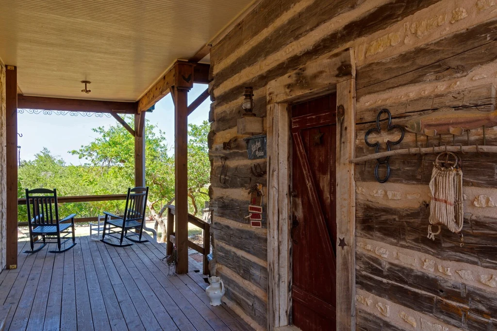 Cowgirl Cabin exterior — log cabin porch with rocking chairs and horseshoes