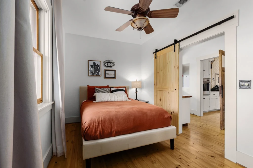 Main House third bedroom — full-size bed with sliding pine barn door to the kitchen