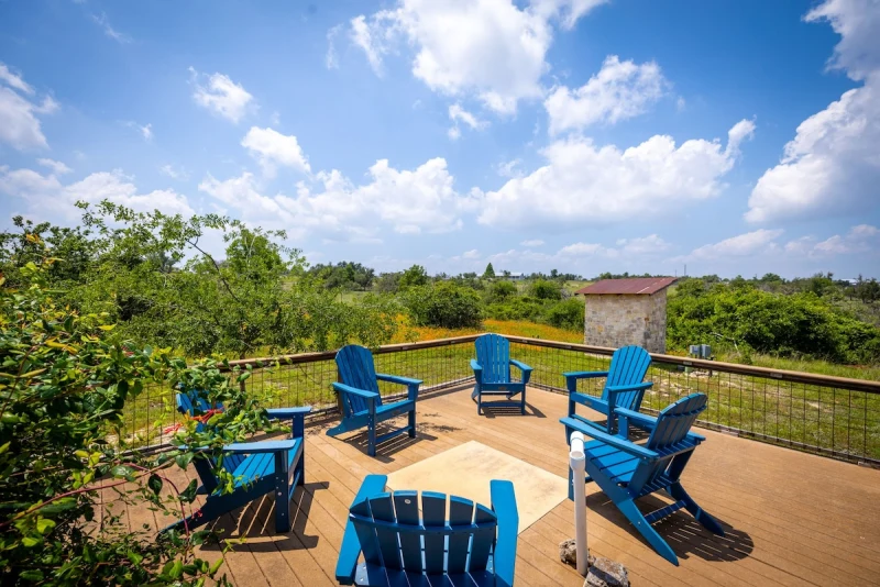 Circular cedar deck with blue Adirondack chairs and wide Hill Country sky