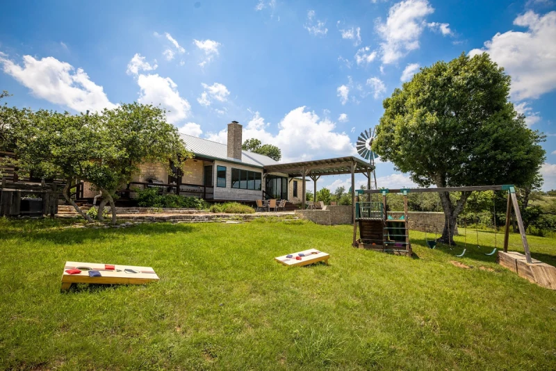 Backyard behind the Main House with cornhole, swing, and windmill