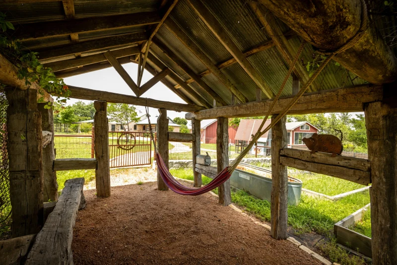 Rustic timber pavilion with a red hammock and the ranch view behind