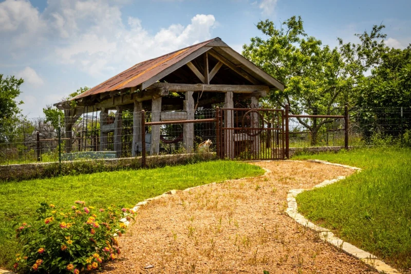 Rustic timber pavilion with stone path and yellow wildflowers