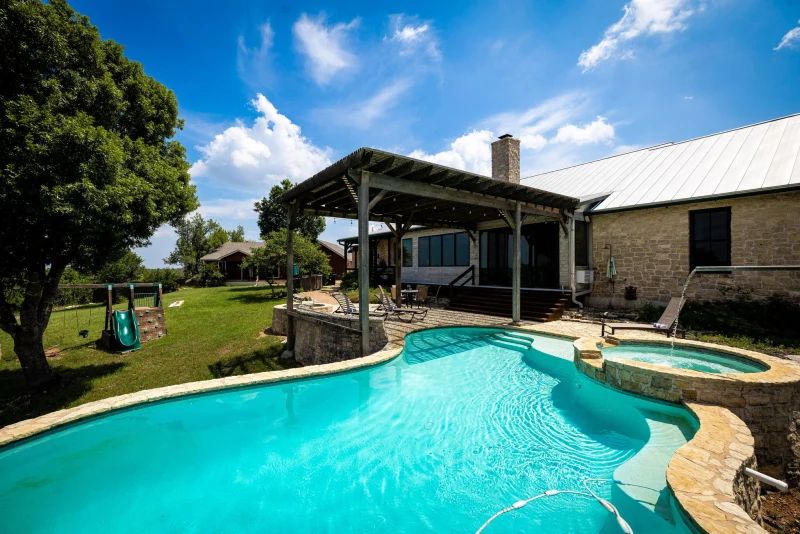 Pool and hot tub under the covered patio, Main House stone wall behind