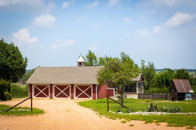 Red workshop barn with three white X doors across the property