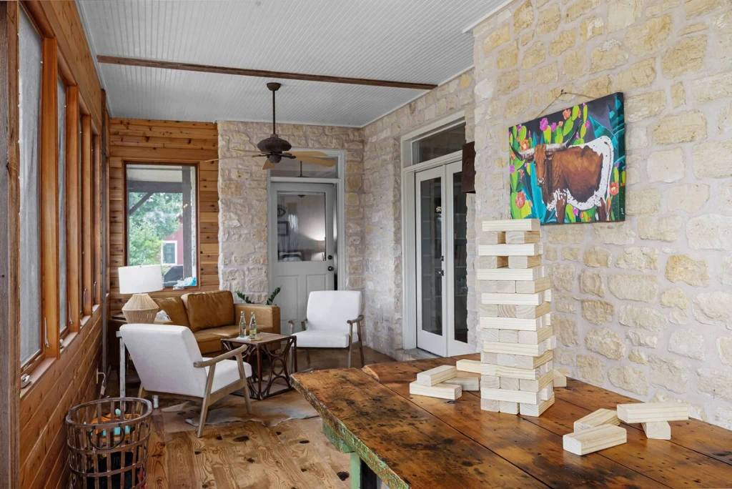 Sun porch and game room with limestone and wood walls, giant Jenga, and cornhole